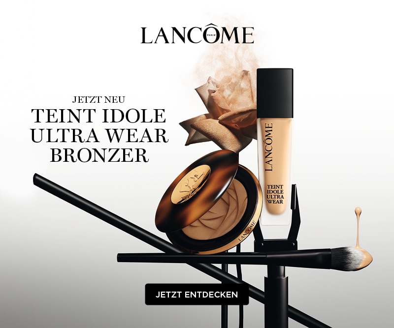 Lancôme Jetzt Neu Teint Idole Ultra Wear Bronzer - einer geöffneten Bronzer-Dose, einer Flasche Lancôme Teint Idole Flüssigfoundation und einem Make-up-Pinsel auf einem weiß-grauen Farbverlauf-Hintergrund mit einer roséfarbenen Blume im Nude-Ton.